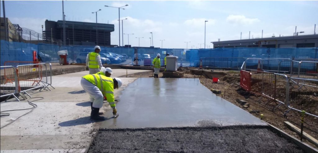 Freshly poured concrete airside slab with TAG operatives finishing it, CP12 airlock project at Heathrow