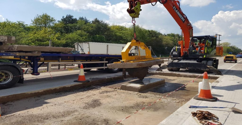 Excavator placing a precast slab during M54 bay replacements
