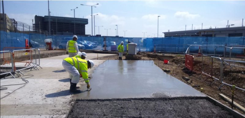 Freshly poured concrete airside slab with TAG operatives finishing it, CP12 airlock project at Heathrow
